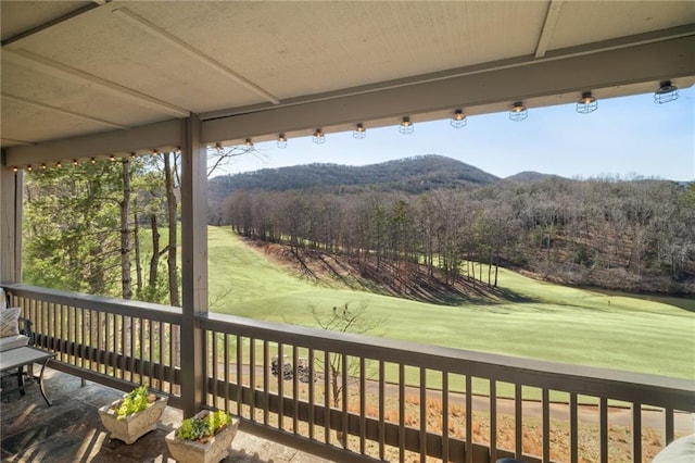 deck with a mountain view, a yard, and a wooded view