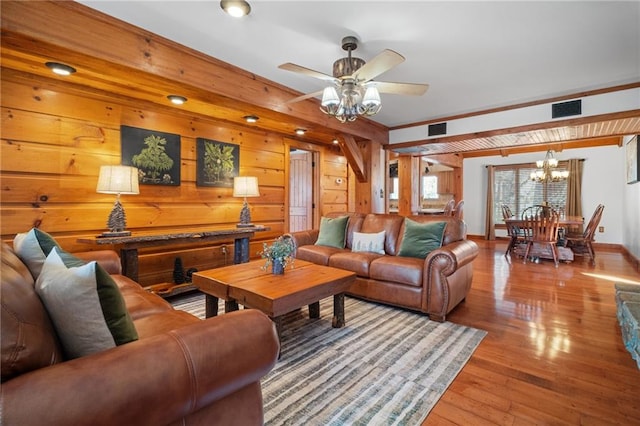 living area with ceiling fan with notable chandelier, visible vents, wood-type flooring, and baseboards