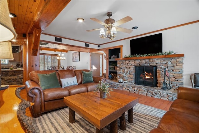 living room with visible vents, ornamental molding, a ceiling fan, wood finished floors, and a fireplace