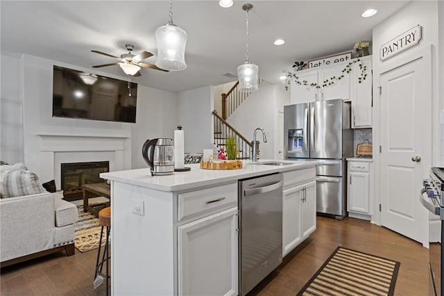 kitchen with sink, white cabinetry, decorative light fixtures, an island with sink, and stainless steel appliances