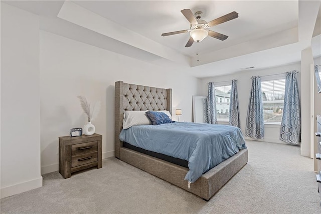 bedroom with ceiling fan, a raised ceiling, and light colored carpet