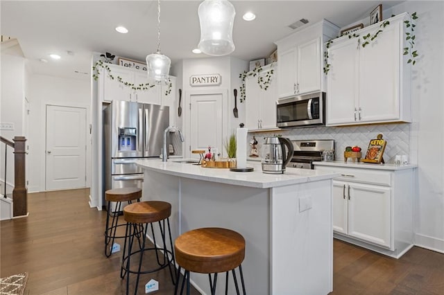 kitchen featuring pendant lighting, tasteful backsplash, sink, stainless steel appliances, and a center island with sink