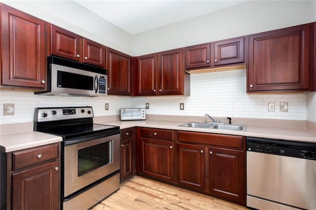 1122 Cotton Gin Dr, Woodstock, GA 30188 - kitchen featuring stainless steel appliances, a sink, light countertops, light wood-style flooring, and tasteful backsplash