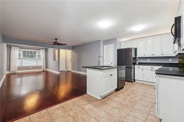 kitchen featuring light wood-type flooring, sink, an island with sink, white cabinets, and ceiling fan