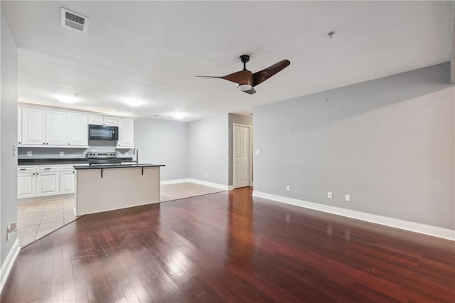 unfurnished living room with ceiling fan, light wood-type flooring, and sink