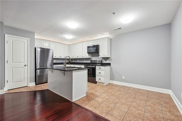 kitchen with a kitchen breakfast bar, white cabinetry, light hardwood / wood-style floors, and appliances with stainless steel finishes