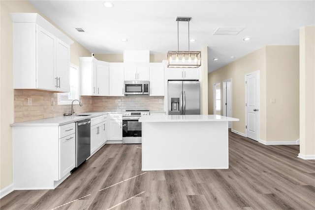 kitchen with visible vents, decorative backsplash, appliances with stainless steel finishes, a sink, and a kitchen island