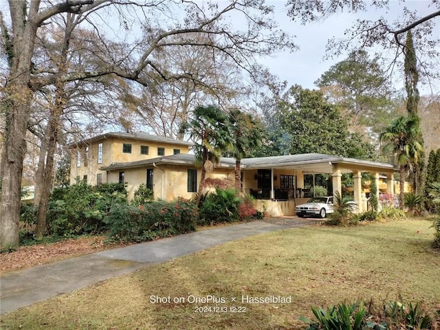 view of front facade with aphalt driveway, a front yard, a carport, and stucco siding