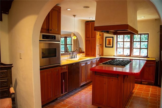 kitchen featuring a center island, a sink, island exhaust hood, stainless steel oven, and gas cooktop