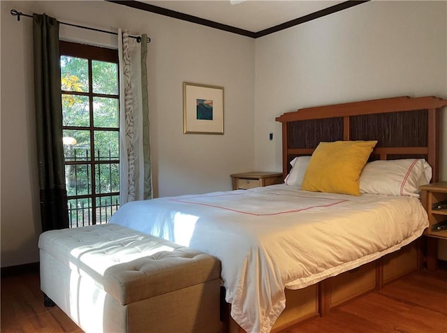 bedroom with ornamental molding and wood finished floors