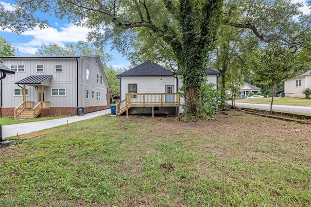 rear view of property featuring a lawn and a deck