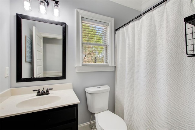 full bath with toilet, vanity, curtained shower, and baseboards