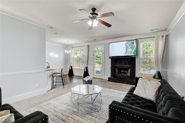 living area with ornamental molding, carpet flooring, healthy amount of natural light, a ceiling fan, and wainscoting