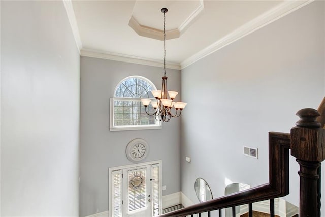 detailed view of a chandelier, ornamental molding, and a tray ceiling