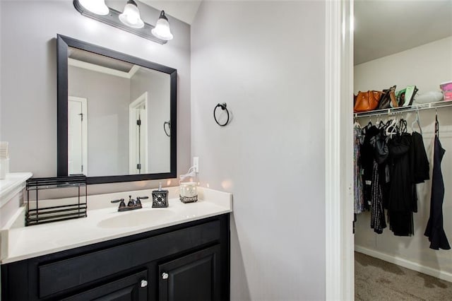 bathroom featuring a walk in closet, vanity, and baseboards
