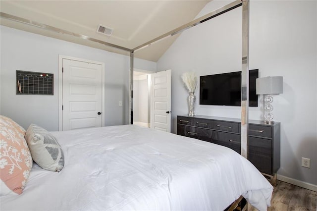 bedroom featuring wood finished floors, lofted ceiling, baseboards, and a closet
