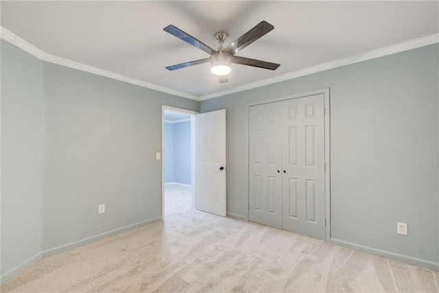 unfurnished bedroom with baseboards, crown molding, carpet floors, a closet, and a ceiling fan