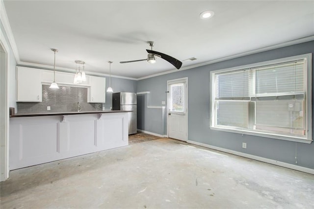 kitchen featuring freestanding refrigerator, dark countertops, white cabinetry, decorative backsplash, and hanging light fixtures