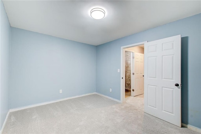 unfurnished bedroom featuring light carpet and baseboards