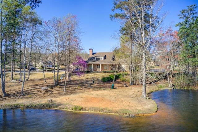 back of house with a water view and a chimney