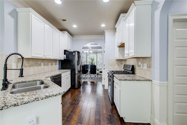 kitchen with appliances with stainless steel finishes, a sink, arched walkways, light stone countertops, and recessed lighting