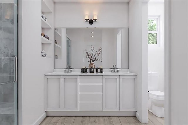 bathroom with an enclosed shower, vanity, hardwood / wood-style flooring, and toilet