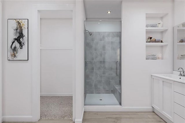 bathroom featuring built in shelves, vanity, an enclosed shower, and wood-type flooring