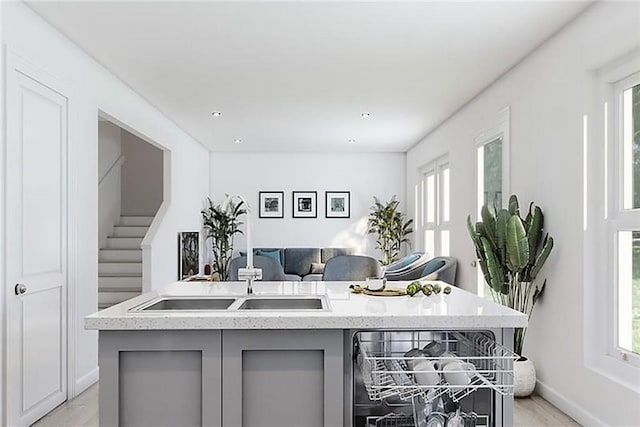 kitchen featuring an island with sink, light hardwood / wood-style flooring, sink, and gray cabinetry