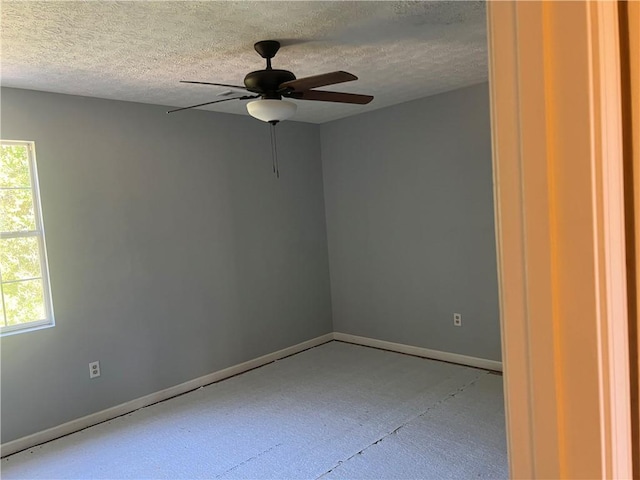 empty room with ceiling fan, a textured ceiling, and a healthy amount of sunlight