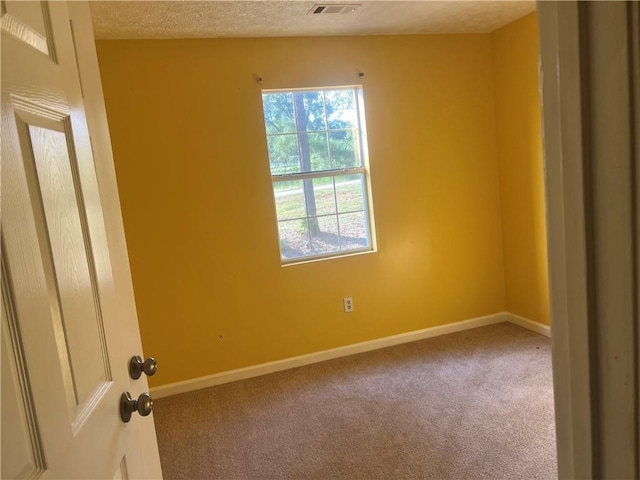 carpeted empty room with a textured ceiling