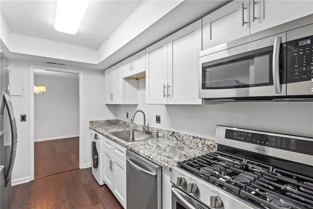 kitchen featuring light stone countertops, appliances with stainless steel finishes, sink, washer / dryer, and white cabinetry