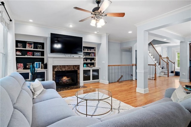 living room featuring a high end fireplace, wood-type flooring, built in features, and crown molding