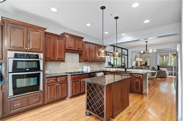 kitchen featuring appliances with stainless steel finishes, sink, dark stone countertops, kitchen peninsula, and pendant lighting