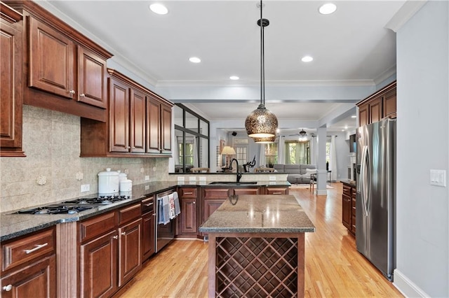 kitchen featuring appliances with stainless steel finishes, a center island, decorative light fixtures, dark stone counters, and crown molding