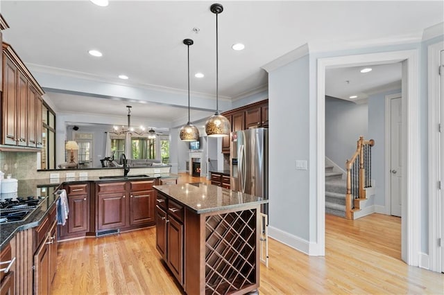 kitchen with pendant lighting, appliances with stainless steel finishes, a center island, sink, and crown molding