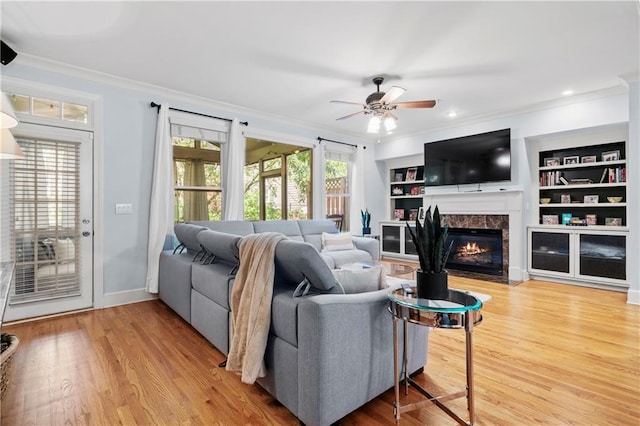 living room with crown molding, built in features, a healthy amount of sunlight, and a high end fireplace