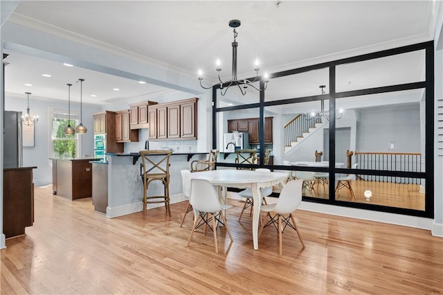 dining room with light hardwood / wood-style floors, a notable chandelier, and ornamental molding