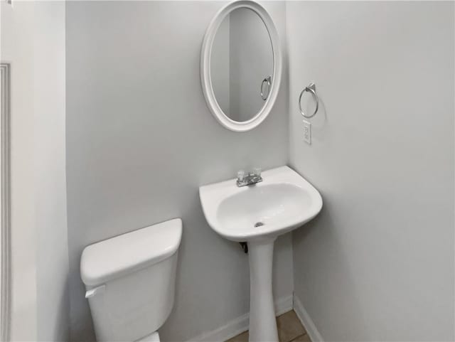 half bath featuring toilet and baseboards