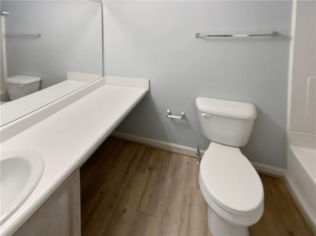 bathroom with baseboards, vanity, toilet, and wood finished floors