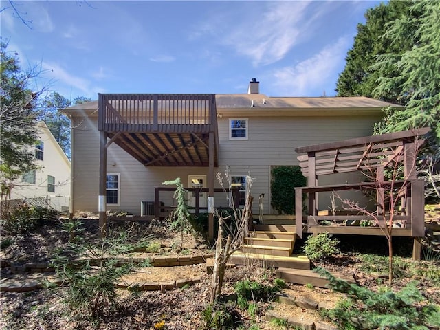 rear view of property featuring a chimney and a deck