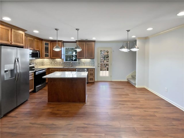 kitchen featuring tasteful backsplash, a kitchen island, dark wood-style flooring, stainless steel appliances, and a sink