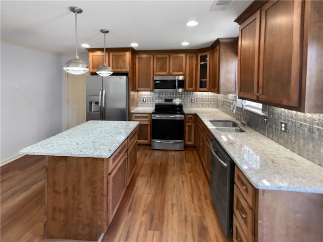 kitchen featuring stainless steel appliances, decorative backsplash, brown cabinetry, dark wood-type flooring, and a sink