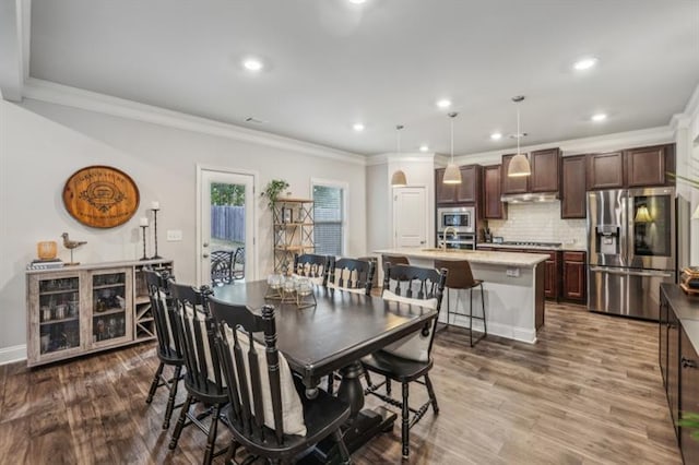 dining space featuring crown molding, dark hardwood / wood-style flooring, and sink