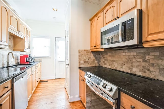 kitchen with sink, ornamental molding, dark stone counters, and appliances with stainless steel finishes