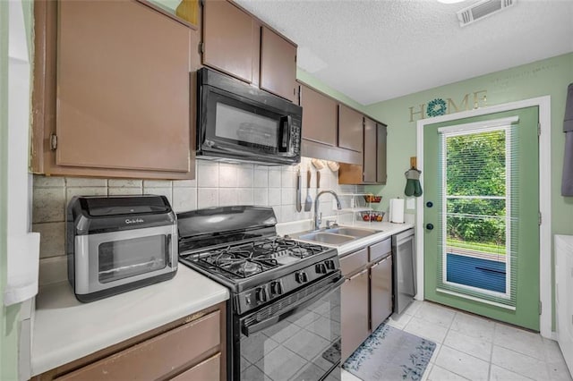 6178 Field Stone Dr, Douglasville, GA 30134 - kitchen with black appliances, decorative backsplash, a textured ceiling, light countertops, and light tile patterned floors
