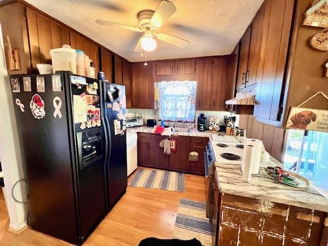 kitchen with under cabinet range hood, light countertops, electric stove, black fridge with ice dispenser, and a ceiling fan