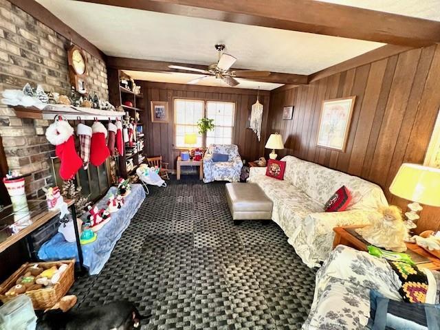 carpeted living room featuring beamed ceiling, wood walls, and ceiling fan