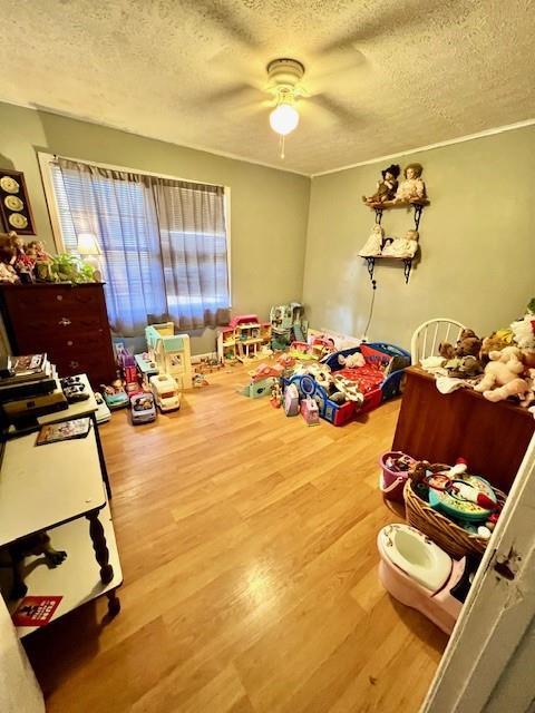 playroom with a textured ceiling, wood finished floors, and a ceiling fan