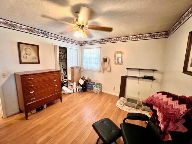 interior space with ceiling fan, light wood-style flooring, and a textured ceiling
