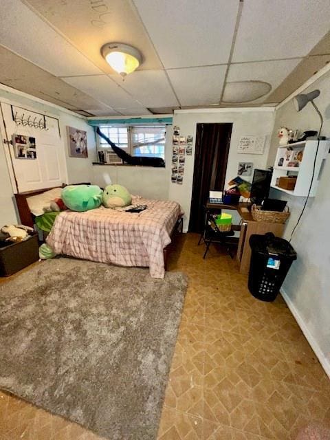 bedroom with a drop ceiling and baseboards